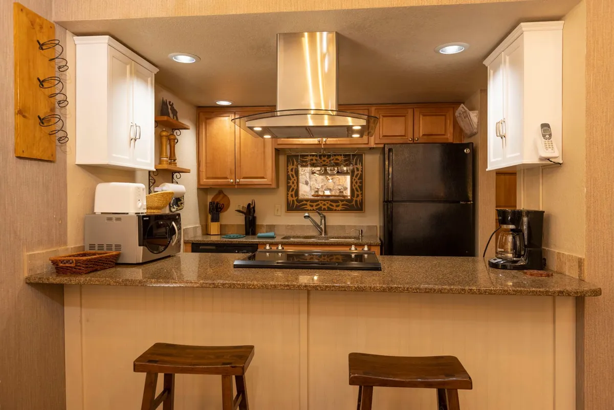 This image showcases a welcoming kitchen with a prominent kitchen island, stools for casual dining or conversation, stainless steel appliances, and ample cabinetry. The layout encourages meal preparation and social interaction, embodying the heart of a home where families can gather.